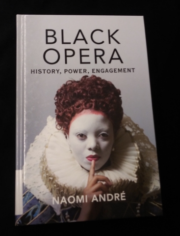 The cover of the book Black Opera with a black woman wearing an elizabethan ruff collar, curly red hair and white face paint.