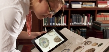 A librarian compares the digital version of a book on an iPad to the original book on a table.
