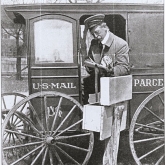 BW photo of post man half sitting in US Mail cart